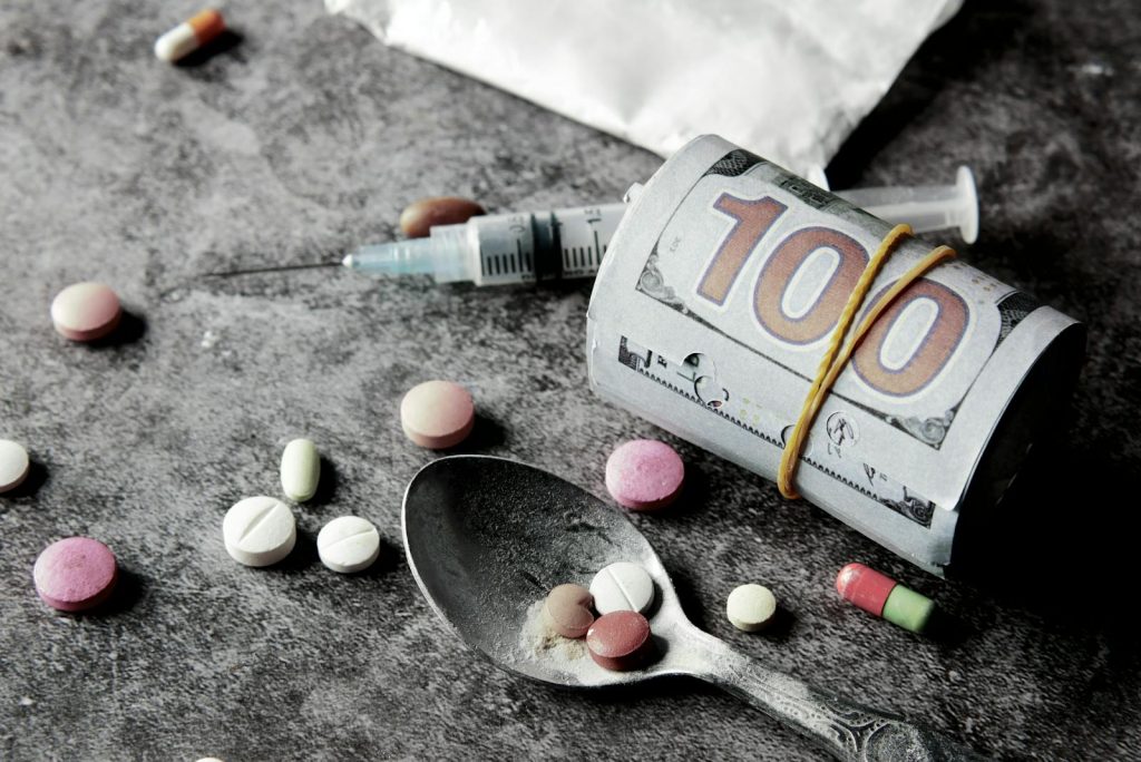 Symbolic representation of drug addiction and financial cost with pills and money.